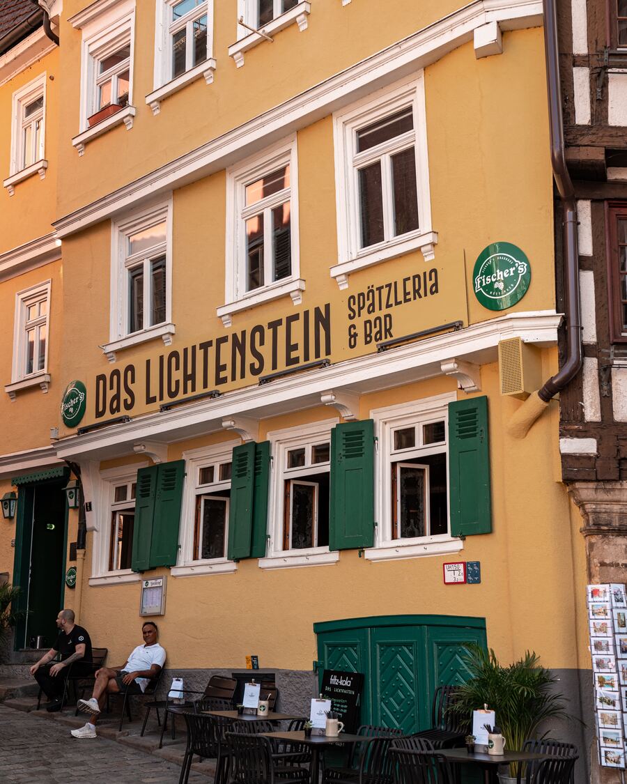 Die gelbe Fassade des Lichtenstein mit Tischen auf dem Kopfsteinpflaster